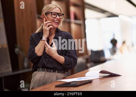 Una donna allegra e professionale impegnata in una conversazione telefonica vivace, che mostra le sue abilità Foto Stock