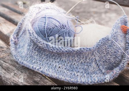 Palla in filato di lana blu e bianca con aghi per maglieria e marcatore. Lana blu e mohair bianco con un bel motivo a maglia. Hobby per lavorare a maglia. Foto Stock