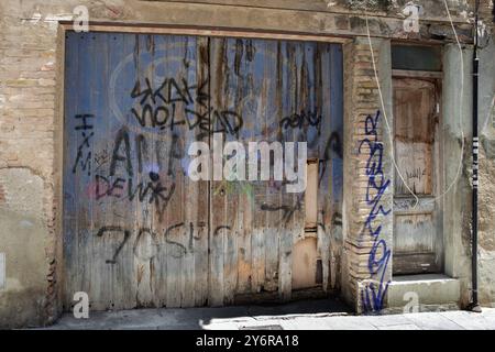 Graffiti su vecchie porte di garage in legno e pareti di un edificio a Cambrils, Costa Dorada, Catalogna, Spagna Foto Stock