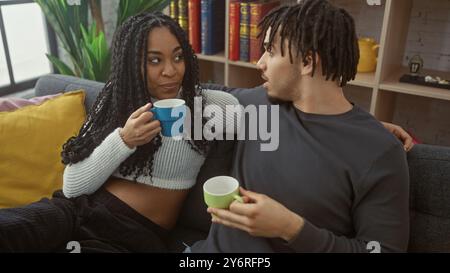 Una giovane coppia gode di un momento intimo con un caffè in un moderno soggiorno. Foto Stock