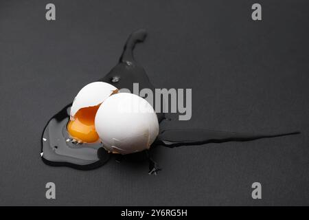 Uovo crudo rotto su sfondo nero, primo piano Foto Stock