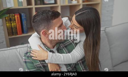 Una coppia amorevole abbraccia su un divano, gioiosamente insieme in un soggiorno accogliente e decorato con gusto. Foto Stock