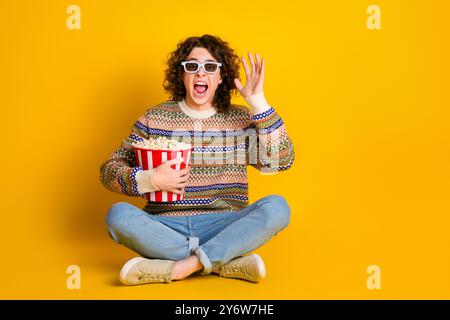 Foto a grandezza naturale di un maglione ornamentale vestito da ragazzo terrorizzato con occhiali 3d Sit hold popcorn Watch horror isolato su sfondo giallo Foto Stock