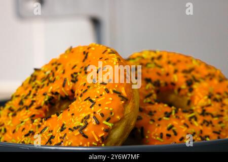 Due ciambelle a tema Halloween con glassa arancione, spruzzette di bianco e nero Foto Stock
