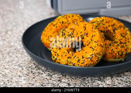 Tre ciambelle a tema Halloween con glassa arancione, spruzzette di bianco e nero Foto Stock