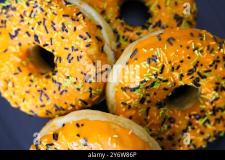 Ciambelle a tema Halloween con glassa arancione, spruzzi di bianco e nero, vista dall'alto Foto Stock