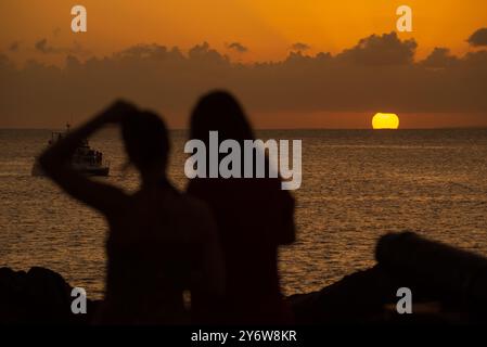 Salvador, Bahia, Brasile - 21 dicembre 2019: Due persone in sagoma si godono il tramonto al porto di barra a Salvador, Bahia. Foto Stock