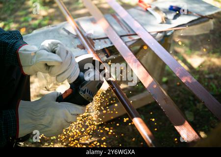 Primo piano di un lavoratore che taglia tubi metallici con una smerigliatrice angolare Foto Stock