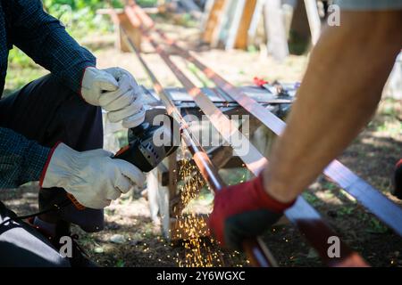 Primo piano di un lavoratore che taglia tubi metallici con una smerigliatrice angolare Foto Stock