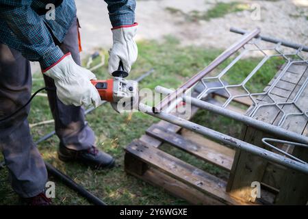 Primo piano di un uomo che smeriglia il telaio in metallo all'aperto Foto Stock