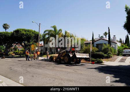 Lavori di ripavimentazione di strade con lavoratori e macchinari coinvolti attivamente nel processo. L'attrezzatura include un bulldozer e un dumper. Foto Stock