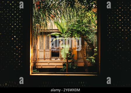 All'interno di un riad tradizionale marocchino, finestre interne in legno, alloggi di lusso, cortile interno con lussureggiante vegetazione tropicale, piante, viti e flowe Foto Stock