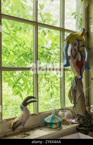 Sculture di uccelli di Toucan e altri oggetti antichi in vendita sul davanzale della finestra all'interno del negozio di articoli di seconda mano e chattels. Foto Stock