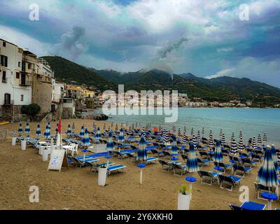 Una vista panoramica di una spiaggia mediterranea con file di ombrelloni e lettini a righe blu e bianche. Foto Stock