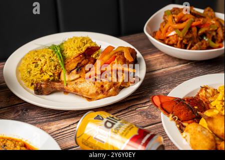 Una deliziosa varietà di piatti, tra cui pollo alla griglia con riso, aragosta e verdure miste, su un rustico tavolo in legno. Foto Stock