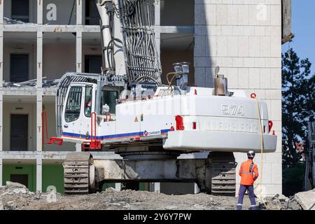 Vista su un escavatore cingolato bianco Liebherr R 974 C che demolisce un complesso di uffici. Foto Stock