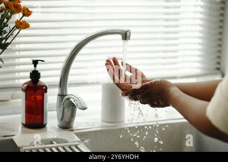 Lavare le mani sotto l'acqua corrente nel lavello della cucina Foto Stock