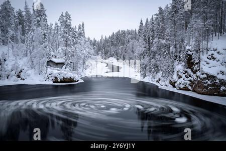 Fiume con blocchi di ghiaccio che si snodano nelle rapide di Myllykoski, sul fiume Kitkajoki, tutto coperto di neve in inverno nel Parco Nazionale di Oulanka. Juuma Kuusamo Finlandia Foto Stock