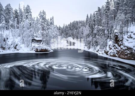 Fiume con blocchi di ghiaccio che si snodano nelle rapide di Myllykoski, sul fiume Kitkajoki, tutto coperto di neve in inverno nel Parco Nazionale di Oulanka. Juuma Kuusamo Finlandia Foto Stock