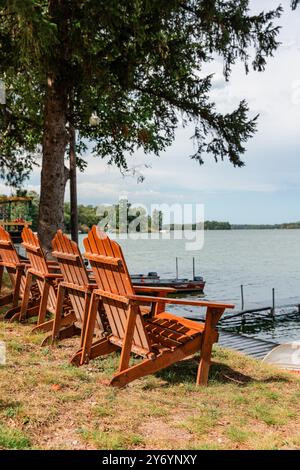 Sedie Adirondack che si affacciano sul lago lungo la costa Foto Stock