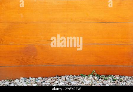Una tavola orizzontale di legno di colore marrone con nodi sulla superficie e piccole pietre sul fondo. Trama o sfondo Foto Stock