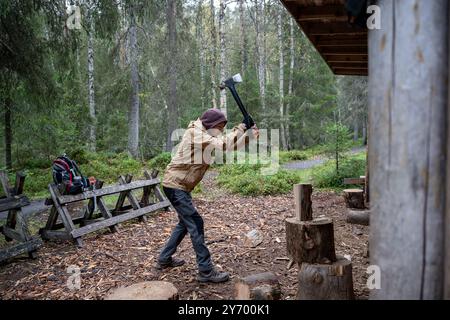 uomo che taglia legna da ardere con un'ascia per fare un fuoco nella foresta Foto Stock