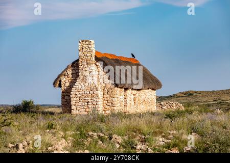 La sola casa di pietra, intemprata dagli elementi duri, sorge in mezzo al paesaggio arido del deserto del Kalahari, in Sudafrica Foto Stock