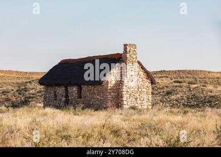 La sola casa di pietra, intemprata dagli elementi duri, sorge in mezzo al paesaggio arido del deserto del Kalahari, in Sudafrica Foto Stock