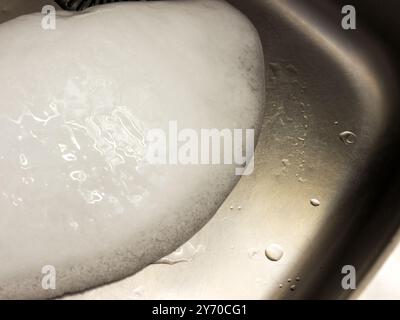 Un pezzo di ghiaccio in un lavandino di metallo. Foto Stock