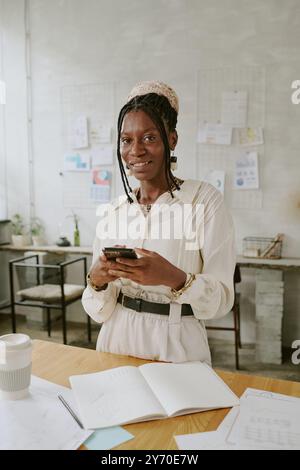 Ritratto di una donna d'affari afroamericana sorridente con smartphone in mano Foto Stock