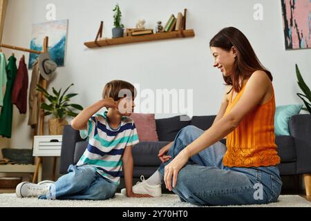 Una madre si impegna scherzosamente con il figlio con problemi di udito nel loro caldo spazio abitativo. Foto Stock