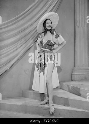 MODA PARIGINA IN SFILATA DA TELEVIEWERS INGLESI nuove mode primaverili ed estive portate in particolare da Parigi e modellate da manichini francesi sono presenti in un programma televisivo di Alexandra Palace ( Londra ) . Le creazioni provengono da designer di fama mondiale come Balmain , Faith , Molyneux , Piguet e Schiaparelli , e gli spettatori possono confrontarle con le mode britanniche recentemente trasmesse in televisione . LA FOTO MOSTRA :- Un costume da spiaggia ( di Balmain ) in piquet bianco con fiori verdi - il cappello è di paglia bianca . La tuta è vista modellata da CAROLE in una prova pre-podcast ad Alexandr Foto Stock
