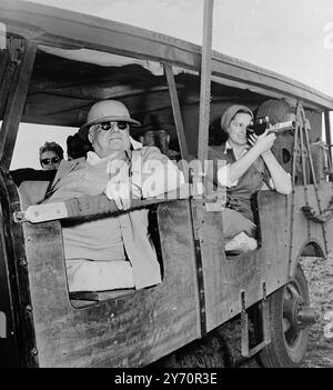 73 anni Aga Khan ' Croesus ' - il Begum (a destra) viene visto al lavoro con una macchina fotografica telescopica durante la spedizione guardato dall'Aga Khan in occhiali scuri. Erano in safari per fotografare animali selvatici nella giungla dell'Africa orientale. La spedizione costò USD4000 al giorno e il campo fu dotato di splendidi e confortevoli appartamenti. 1950 Foto Stock