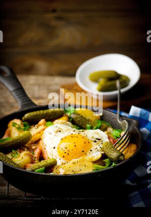 Paese prima colazione a partire da patate, con pancetta e uova fritte in una ghisa di padella. stile rustico. messa a fuoco selettiva Foto Stock