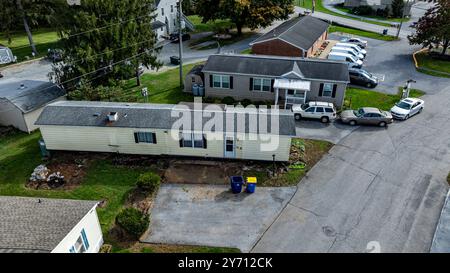 Diversi rimorchi residenziali fiancheggiati lungo una strada suburbana, che mostrano la disposizione dell'area e i parcheggi nelle vicinanze. Alberi e cortili ben mantenuti valorizzano il paesaggio. Foto Stock