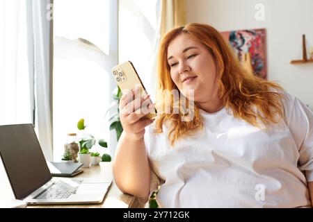 Una donna radiosa e di grandi dimensioni si impegna con il suo smartphone, circondato dal verde e dalla luce del sole. Foto Stock