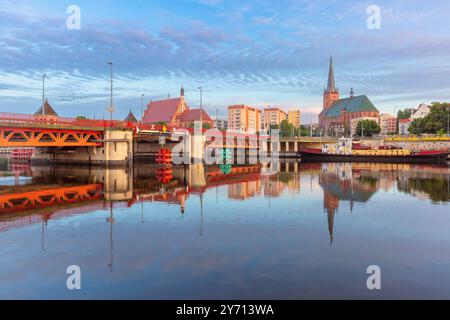 Vista mattutina di un ponte e della cattedrale di San Giacomo a Szczecin, Polonia, con chiari riflessi nelle acque calme del fiume Oder, incorniciate dall'architettura della città Foto Stock