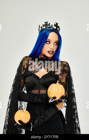 Vestita con uno splendido costume di Halloween, cattura l'attenzione con le sue zucche e la posa giocosa. Foto Stock