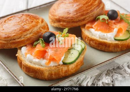 Sandwich con salmone salato, formaggio spalmabile, cetrioli freschi e olive da vicino su un piatto sul tavolo. Orizzontale Foto Stock