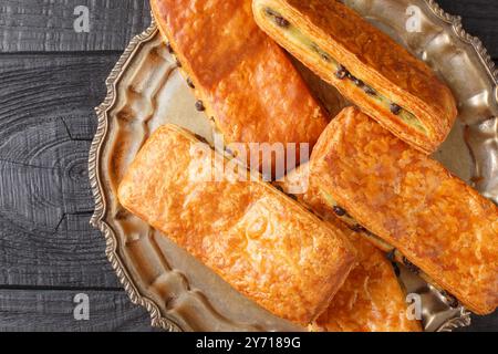 Buns Pain Suisse è composto da pasta di croissant, crema di pasticceria alla vaniglia fatta in casa e gocce di cioccolato costellate durante il primo piano sul piatto del tavolo. Hori Foto Stock