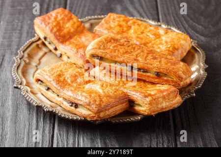 Il Pain Suisse au Chocolat è realizzato con croissant perfetti, ripieno di crema pasticcera fatta in casa vellutata e di gocce di cioccolato da vicino sul piatto Foto Stock