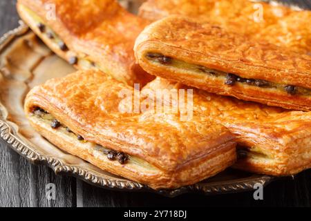 Buns Pain Suisse è composto da pasta di croissant, crema di pasticceria alla vaniglia fatta in casa e gocce di cioccolato costellate durante il primo piano sul piatto del tavolo. Hori Foto Stock