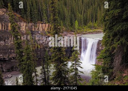 Potente cascata che scende giù da una scogliera rocciosa circondata da una lussureggiante foresta sempreverde Foto Stock