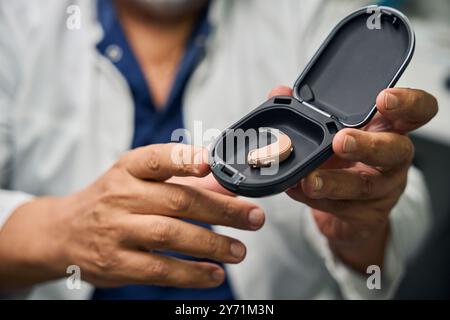 Medico che tiene l'apparecchio acustico in un caso aperto Foto Stock