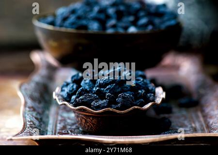 Essiccato l'uvetta scura in metallo orientali ware. stile vintage messa a fuoco selettiva. Foto Stock