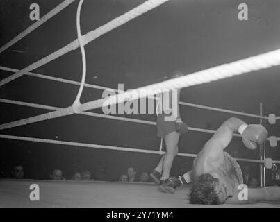 WOODCOCK B OMA FIGHT ALL'HARRINGAY, campione britannico di pugilato dei pesi massimi, BRUCE WOODCOCK, tornò sul ring dopo 17 mesi di assenza. Quando ha combattuto LEE OMA di Chicago, in una gara di otto round ad Harringay . L'ultimo incontro di Woodcock fu su questo stesso ring, quando ebbe la mascella fratturata e Eye danneggiato nel suo combattimento con un altro americano JOE Baksi . LA FOTO MOSTRA:- Winning Blow Woodcock si allontana dopo aver mandato Oma schiantarsi sulla tela . 21 settembre 1948 Foto Stock