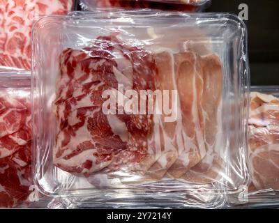 Salumi misti in vassoio di plastica sottovuoto, fette di prosciutto e salame e fette di pancetta Foto Stock