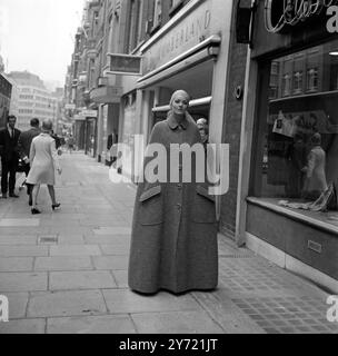 La modella Suzy si trova a pochi passi dalla Christian Dior - London Fashion House in Conduit Street, in un mantello senza maniche, lunghezza del pavimento, in tweed grigio. Pochi istanti dopo ha smontato i cinque bottoni sagomati per rivelare una gonna in patchwork in tweed grigio e una blusa in chiffon a pieghe da indossare a casa. il mantello , la gonna e la camicetta sono della nuova collezione Autunno 1969 di Christian Dior - Londra . La collezione è stata degnata da Jorn Langberg . 9 settembre 1969 Foto Stock