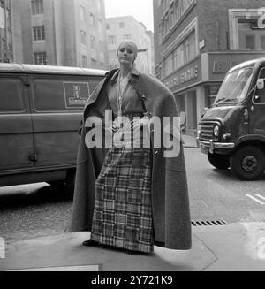 La modella Suzy si trova a pochi passi dalla Christian Dior - London Fashion House in Conduit Street, in un mantello senza maniche, lunghezza del pavimento, in tweed grigio. Pochi istanti dopo ha smontato i cinque bottoni sagomati per rivelare una gonna in patchwork in tweed grigio e una blusa in chiffon a pieghe da indossare a casa. il mantello , la gonna e la camicetta sono della nuova collezione Autunno 1969 di Christian Dior - Londra . La collezione è stata degnata da Jorn Langberg . 9 settembre 1969 Foto Stock