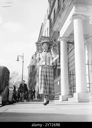 Primavera a Mayfair. Questa giovane signora si è fermata fuori dalle sfilate di moda e al sole di Bruton-Street, Mayfair, questa mattina (giovedì). Il suo vestito aveva una giacca corta in lana grigia con prugna che enfatizza l'anca, e la lunga gonna a quadri svasata ha un suggerimento di Scozia che è stato abbinato all'ombrello tartan. 18 marzo 1948. Foto Stock